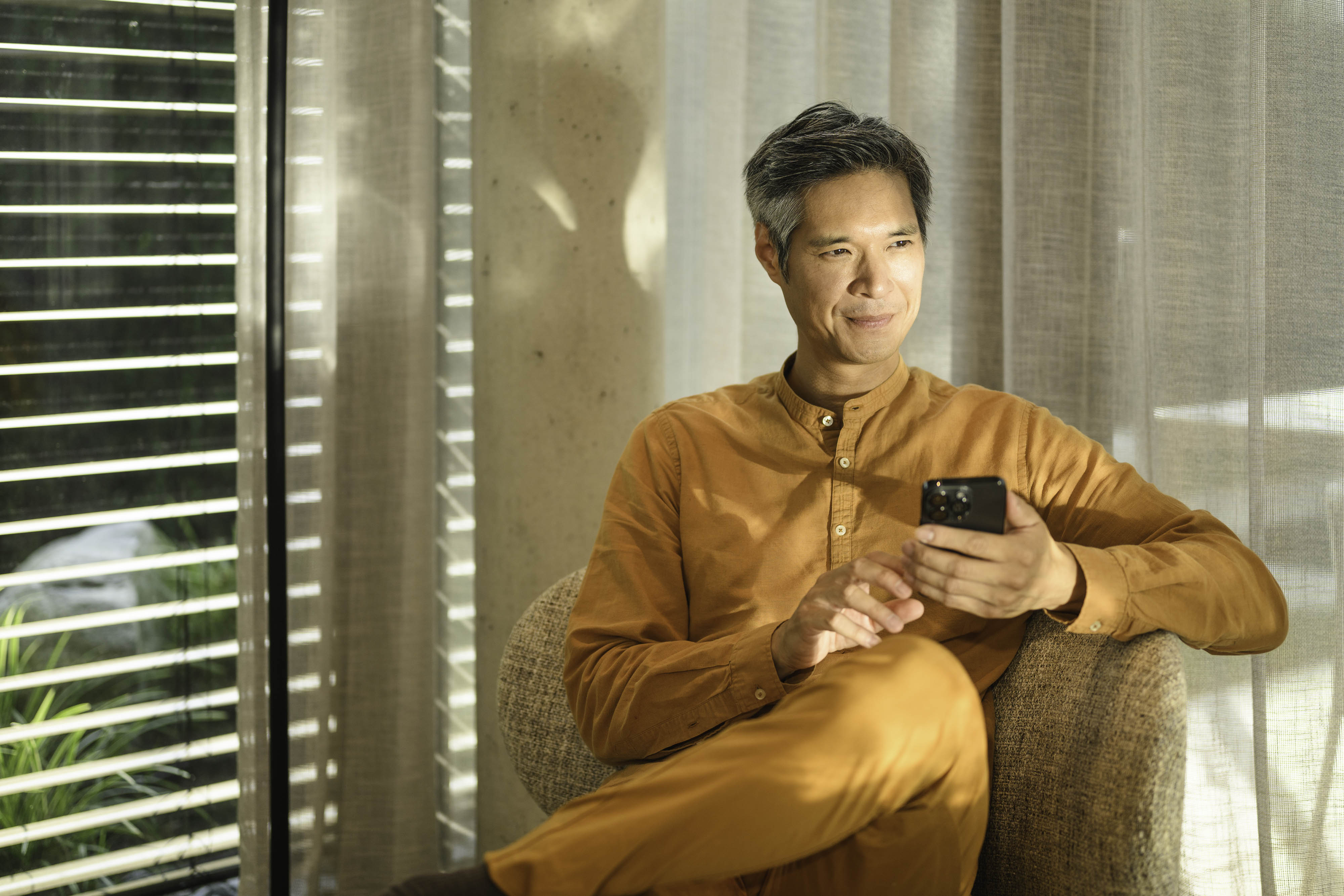 查閱現有客戶的帳戶詳情 一人座於梳化上流動設備,手持及向遠處眺望